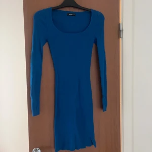 Blå ribbad långärmad klänning - Snygg blå ribbad klänning från new yorker med lång ärm och tight passform. Klänningen har en fyrkantig urringning och är kort i modellen.