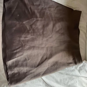 Brun satinkjol från BikBok XS - Säljer en brun kjol från BikBok i satinliknande material. Passformen är rak och midjan är normalhög. Har några fläckar som man kan se på sida 3 & 4, ingen anning vart de kommer ifrån så vet inte om de går bort eller inte. 