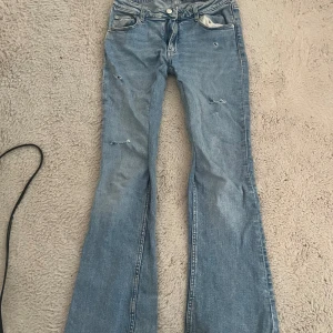 Bootcut jeans från Gina Tricot - Snygga ljusblå bootcut jeans från Gina Tricot med slitna detaljer som jag gjort själv, jag har även sytt dem så de ska bli lite mer low waist!