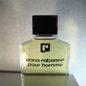 Vintage Paco Rabanne Pour Homme After Shave  75 ml - Klassisk After Shave  från Paco Rabanne i en stilren, transparent glasflaska med svart fyrkantigt lock. Innehåller 75 ml doftvätska i en fräsch grön-gul nyans. Perfekt för dig som gillar tidlösa och maskulina dofter.