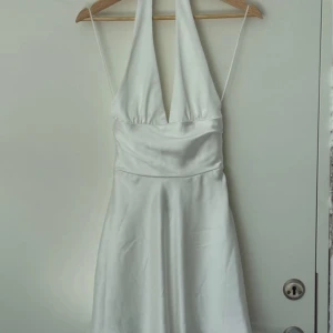 Vit satin klänning från zara - En halter neck klänning i vit satin ifrån zara. Nyskick i storlek XS prislappen är kvar på. Säljs nog inte längre och Säljer då jag aldrig fått användning för den och har andra liknande💕