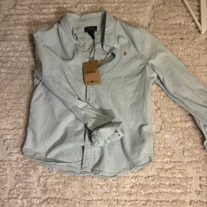 Ralph lauren skjorta - Säljer denna skjorta från Ralph lauren för bara 150kr! Skjortan är i storlek 14 men skulle själv säga att den passar bäst på någon mellan 11-12