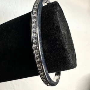 Vintagearmband från 80-/90-tal med strass – klassisk glamour - Silverfärgat vintagearmband med infattade klara strasstenar i tidstypisk 80-/90-talsstil. Elegant och stiligt med klicklås – passar både vardag och fest. Ca 5,2 x 6,2 cm i innermått. I fint skick med mindre spår av användning. Ingen prutning – men jag erbjuder rabatt vid köp av flera saker. Rensar smyckesskrin och garderob, så kika gärna på mina andra annonser också!  ⸻  