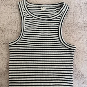 Randig ribbad linnetopp  - Säljer en svartvit randig ribbad linnetopp från DF YOUNG i storlek XS. Toppen är ärmlös med klassisk rund halsringning och smal passform. Perfekt för dig som gillar en enkel men stilren look med lite edge.