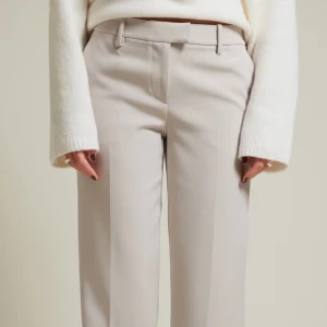 Ljusgrå/beiga kostymbyxor från Bik Bok - Snygga ljusgrå/beiga  kostymbyxor från Bik Bok i klassisk rak modell. Byxorna har hällor för bälte, sidfickor och stängs med dragkedja och knapp. Perfekta för en clean och stilren look. Materialet känns mjukt och har en lätt struktur. Använd 1 gång!