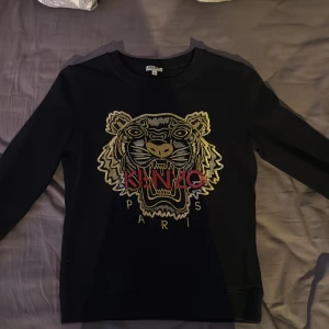 Svart Kenzo tröja  - Svart tröja från Kenzo i storlek XS broderat tigerhuvud och Kenzo Paris-logga framtill. Tröjan har rund halsringning och långa ärmar. 