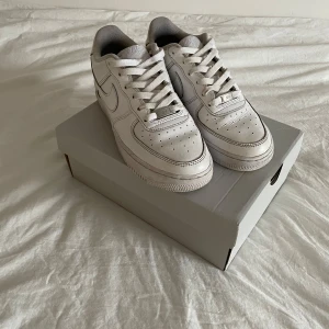 Nike Air Force 1 vita sneakers - Klassiska Nike Air Force 1 sneakers i helvitt skinn med perforerad tå, rund tå och platt sula. Swoosh-logga på sidorna och Nike Air-broderi på hälen. Tidlös modell med snörning och lågt skaft, dom kommer också med orginal boxen och är perfekt för en clean och stilren look till sommaren, priset kan diskuteras vid snabba affärer.