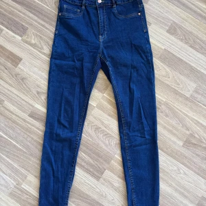 Mörkblå skinny jeans Molly L - Snygga mörkblå skinny jeans från Gina Tricot, modell Molly. Jeansen har klassisk femficksdesign, hög midja och smal passform hela vägen ner. Perfekta för dig som gillar stretchiga och bekväma jeans med enkel look.