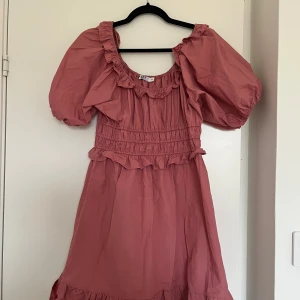 Rosa volangklänning från NA-KD - Supersöt rosa klänning från NA-KD med puffärmar, volangdetaljer och smockad midja. 