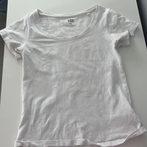 Vit basic t-shirt från 157, XS - En klassisk vit t-shirt från 157 i storlek XS. T-shirten har rund halsringning och korta ärmar. Tillverkad i mjuk bomull med lite stretch för extra komfort. Perfekt att matcha med jeans eller shorts för en enkel och clean look.