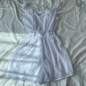 Vit volangjumper - Tunt, luftigt tyg med små prickar i strukturen och bred resår i midjan för en bekväm passform. Perfekta för varma dagar och en söt, somrig look. Aldrig använd, katt finns i hemmet!