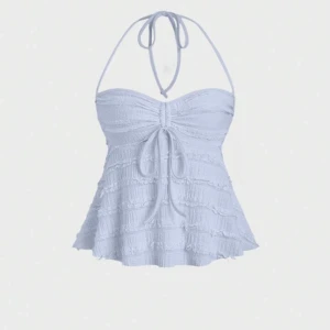 Ljusblå volangig halterneck linnetopp - Supersöt ljusblå linnetopp med volanger och knytning både i nacken och framtill. Toppen har en lätt utsvängd form och smockad struktur som ger en romantisk vibe. Perfekt för varma dagar när du vill känna dig extra fin.