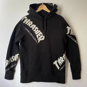 HUF x Thrasher TDS Allover Hoodie - Svart Tour De Stoops-hoodie. TDS är ett samarbete mellan HUF och Thrasher Magazine.   Storlek: M Armhåla till armhåla: 55 cm  Längd: 72 cm  Sökord:  HUF X Thrasher Collab, Allover print, Trasher Worldwide, skate, Street, skateboard, Direct Embroidery, black, svart, Tour De Stoops.