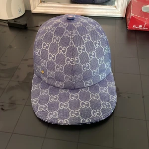 Gucci keps baby blue - Snygg baby blå keps från Gucci i jeansmaterial med ikoniskt GG-mönster över hela kepsen. Klassisk böjd skärm och knapp på toppen. Perfekt för dig som vill sticka ut med en exklusiv accessoar och visa din stil. Använd max 6 gånger, säljer då den är för tajt, billigast du kan få tag på!!