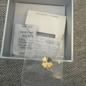 Guldigt halsband med fyrklöver - Snyggt halsband med tunn kedja och ett hängsmycke i form av en fyrklöver i guldig färg. Perfekt accessoar för dig som vill ha något stilrent men ändå unikt. Kommer i originalask.