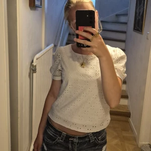 Vit blus med puffärm - vit blus med korta puffärmar och broderade hålmönster. Köpt från Gina Tricot. Blusen har rund halsringning och är lätt croppad. Bra skick! Stl xs/s 