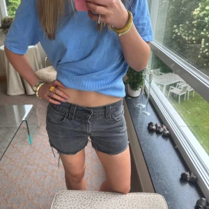 Grå jeansshorts från Levi's low waist  - Snygga grå jeansshorts från Levi's med råa kanter och klassisk femficksmodell. Shortsen har hög midja och en cool, tvättad look. Perfekta för sommardagar när du vill ha en avslappnad men trendig stil.