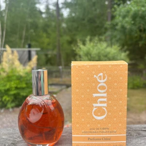 Chloé Eau de Toilette parfym - Chloé Eau de Toilette parfym med en rund glasflaska och silverfärgad spraykork. Parfymen har en varm orange ton och kommer i en snygg orange kartong med vitt mönster och logga. En klassisk och feminin doft från Parfums Chloé.