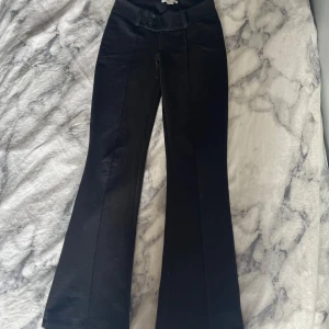 Svarta kostymbyxor från Gina Tricot - Snygga svarta kostymbyxor från Gina Tricot i storlek 152. Byxorna är utsvängda, har låg midja, pressveck och stängs med två knappar framtill. Perfekta om du gillar en klassisk men trendig look. Säljer eftersom de är för korta för mig💞