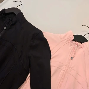 Lululemon Bundle Define Jacket svart & rosa (nytt skick priset kan diskuteras) - Säljer två Lululemon Define Jackets i svart och ljusrosa. Jackorna har figurnära passform, hel dragkedja framtill, hög krage och diskreta loggor. Tillverkade i stretchigt syntetmaterial som andas, perfekta för träning eller chill. Långa ärmar med tumhål och snygga sömdetaljer. (Priset kan diskuteras)