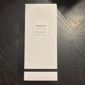 Yves Saint Laurent Babycat EdP 75ml - Exklusiv parfym Babycat från Yves Saint Laurent, 75 ml Eau de Parfum. Parfymen kommer ifrån ysl egna privata linje. Doften har inslag av mocka och vanilj. Flaskan är stilren och rektangulär i genomskinligt glas med svart lock och etikett framtill. Kommer i elegant vit kartong med svart detalj. Den har bara lite mer än 40ml kvar. Hör av er vid minsta lilla fråga eller fundering. Priset är inte hugget i sten. 