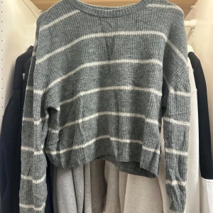Gråvit randig stickad tröja H&M S - Supermysig stickad tröja från H&M Divided i grått med vita horisontella ränder. Tröjan har en rund halsringning och långa ärmar. Perfekt för lager-på-lager och chill dagar.