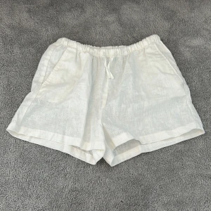 Vita linneshorts från H&M - Jag säljer dem här jätte söta vita linneshortsen från h&m. Shortsen är i storlek 164 men passar även folk som har xs💞Jag har inte använt shortsen alls mycket, bara ett par fåtal gånger! Shortsen har även en elastisk midja och snörning💗