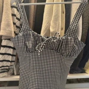 Rutig topp från Zara - Supersöt linnetopp i svartvitt rutigt mönster med smala axelband och söt snörning framtill vid bysten. Toppen är figurnära och har en klassisk, tidlös look som passar perfekt till jeans eller kjol. Perfekt för varma dagar och sommarhäng.