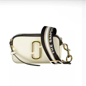 Marc Jacobs Snapshot axelväska beige - Snygg beige och svart axelväska från Marc Jacobs med guldiga metalldetaljer och bred, randig axelrem i svart, beige och vitt. Väskan har en rektangulär form, dragkedja upptill och ikonisk logga framtill. Perfekt för att lyfta din outfit.