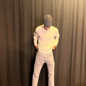 Beige stickad tröja med rund hals - En stilren beige stickad tröja med rund halsringning och ribbade muddar. Tröjan har en klassisk passform och långa ärmar, perfekt att matcha med jeans eller kjol för en clean look. Enkel och tidlös design som funkar året runt.