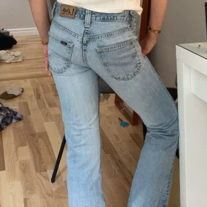 Ljusblå bootcut jeans från Lee - Säljer ett par ljusblå vintage jeans från Lee med bootcut passform. Jeansen har klassisk femficksdesign, låg midja🩷🩷finns en liten  defekt på baksidan, se bild. däremot inget man tänker på alls. Därav priset!!!🌸🌸.mått på bilden! Skulle säga att de är en tajt passform