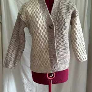 Beige kofta från Zara med strukturmönster - Säljer en beige kofta från Zara med coolt strukturmönster i två olika stilar framtill och på ärmarna. Koftan har v-ringning, knappar och är stickad i mjukt material. Perfekt för lager-på-lager och chill höst- eller vinterstil.