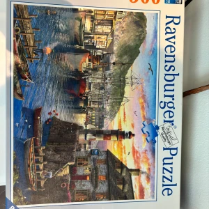 Ravensburger Puzzle (Harbor Scene, 500 bitar) Helt nytt  - Utmanande och roligt pussel med 500 bitar från Ravensburger. Motivet visar en färgstark hamn med båtar, fyr och vackert kvällsljus – perfekt för dig som gillar att koppla av och utmana hjärnan. Passar både unga och vuxna som gillar kreativa aktiviteter.