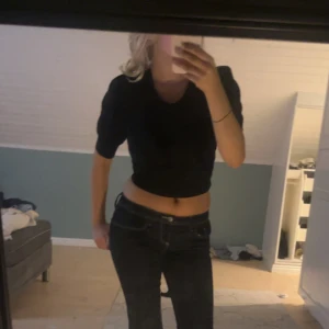 Svart ribbad croppad topp - Säljer en svart croppad topp med ribbad struktur och puffiga korta ärmar. Toppen har rund halsringning och sitter tight mot kroppen, perfekt för en trendig look. Materialet känns mjukt och stretchigt.