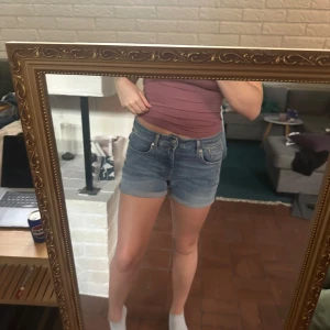 Blå jeansshorts från Replay - Snygga blå jeansshorts från Repaly med klassisk femficksmodell och uppvikta benslut. De har en midwaist passform.