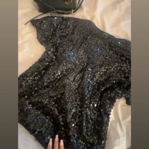 Svart topp med paljetter - Vanlig svart t shirt med paljetter. Perfekt till en svart kjol och ett par klackar. Själv använt under nyår. Inga tecken på användning