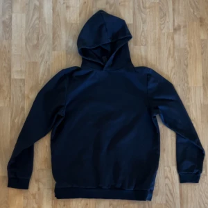 Mörkblå hoodie från SOC i bomull - En stilren mörkblå hoodie från SOC i storlek S. Tröjan har klassisk huva, långa ärmar och ribbade muddar. Materialet är mjuk bomull som känns skönt mot huden.