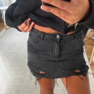 Svart jeanskjol från Hollister - Svart kort jeanskjol från Hollister med slitna detaljer och fransig nederkant. Otroligt fin till sommaren!! Skulle säga att strl motsvarar en s/xs. Använd 2 ggr.