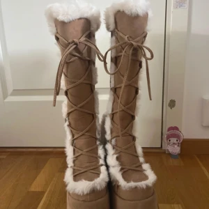 Demonia plattform boots camel 311 - Säljer ett par bruna Demonia boots med hög plattform och chunky klack. Skorna har snörning framtill, dragkedja på sidan och är fodrade med vit fuskpäls längs kanterna. De har varit använda totalt 3 gånger och har inga fläckar eller hål i sig. De skickas med orginal lådan som jag fick de i. Priset på hemsidan är 1700kr men kan sälja de för 1600kr. 