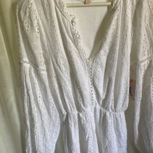 Vit broderad klänning från Nelly - Superfin vit klänning från Nelly med broderade detaljer och v-ringning. Säljer då den var för stor på mig. Klänningen är aldrig använd och prislapp sitter på!💕