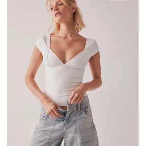 Vit v-ringad topp med kort ärm - Supersnygg vit topp med djup v-ringning och korta ärmar. Figurnära passform som framhäver siluetten och ger en clean look. Perfekt att styla med jeans eller kjol för en trendig vibe.