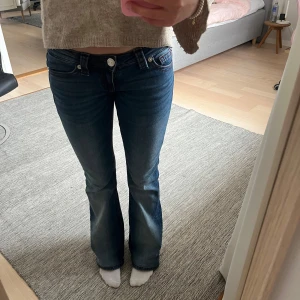 Blå bootcut jeans från Replay - Säljer ett par snygga blå bootcut jeans med röda kontrastsömmar och broderad bakficka. Helt nyköpta! Jag har sytt upp dom vid änden 3 centimeter. Dom är ungefär 94 cm från midjan till fötterna 