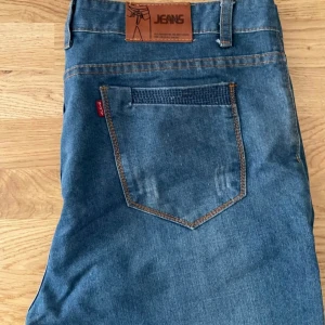 Blå jeansbyxor i rak modell - Snygga blå jeansbyxor i klassisk rak modell med kontrastsömmar och femficksdesign. Byxorna har en normal passform och är tillverkade i tåligt denimtyg. Perfekta för dig som gillar en tidlös och enkel stil.