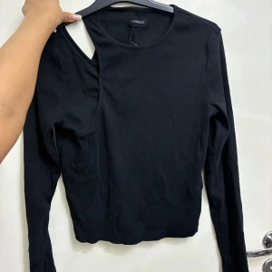 Svart ribbad långärmad topp Even&Odd - Cool svart långärmad topp från Even&Odd med ribbad struktur och unik asymmetrisk cut-out vid axeln. Snygg och trendig design som sticker ut, 