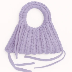 Ljuslila stickad handväska - Superfin handväska i ljuslila med chunky stickat material och runda handtag. Väskan har dekorativa snören som ger en cool och unik look. Perfekt accessoar för att lyfta din outfit med en färgklick.