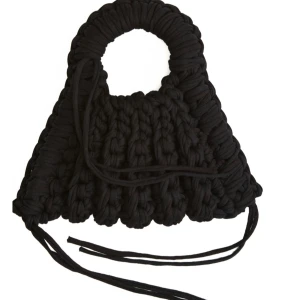 Svart stickad handväska med snörning - Unik svart handväska med grovstickat mönster och rundade handtag. Väskan har dekorativa snören framtill och är perfekt för dig som vill ha en cool accessoar med personlig touch. Tillverkad i mjukt stickat material.