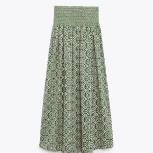 Grön mönstrad långkjol med smock - Långkjol i grönt och vitt med snyggt grafiskt mönster och bred smock i midjan. Kjolen har en luftig passform och faller snyggt. Perfekt för dig som gillar boho-vibe och vill ha något bekvämt men ändå stilrent.