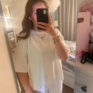 Vit stickad tröja med kort ärm - Superfin vit stickad tröja med korta ärmar och rund hals. Tröjan har en avslappnad passform och ribbade detaljer vid halsringning och nederkant. Perfekt att styla med jeans eller kjol för en clean och fräsch look. Använd en gång 