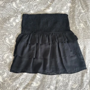 Svart volangkjol från Bik Bok - Svart kjol från Bik Bok med smockad midja och volanger. Använd två gånger och superfint skick❣️ storlek M men passar säkert även S