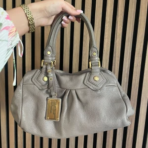 Marc Jacobs väska  - Marc Jacobs classic q baby groove med guldiga detaljer. Väskan är beige. Axelremband ingår. Den är ca 30 cm bred och är i den lilla modellen. Perfekt skick. Fler bilder finns och svarar gärna på frågor 🤍